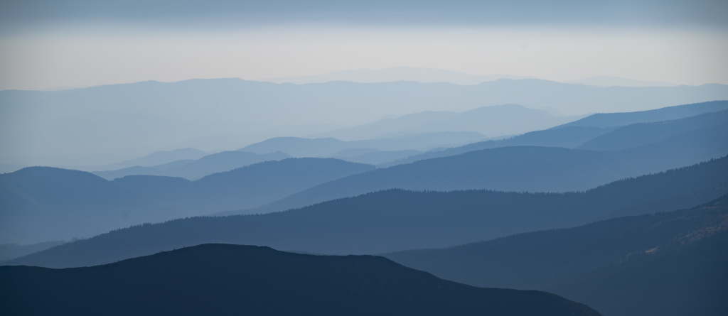 Softly layered mountain silhouettes in muted blue tones.