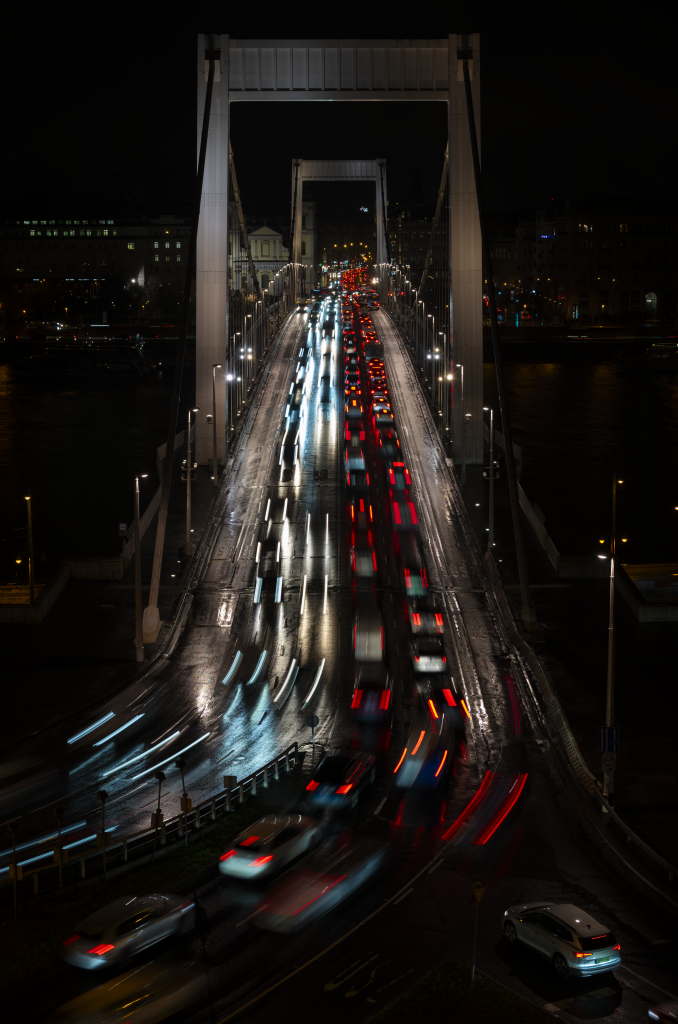 A suspension bridge at night with dense streams of traffic light trails.