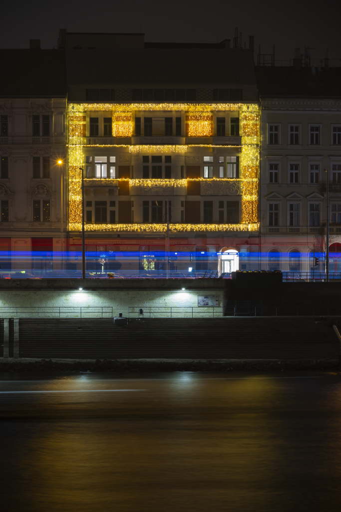Illuminated building facade with horizontal light streaks in front.