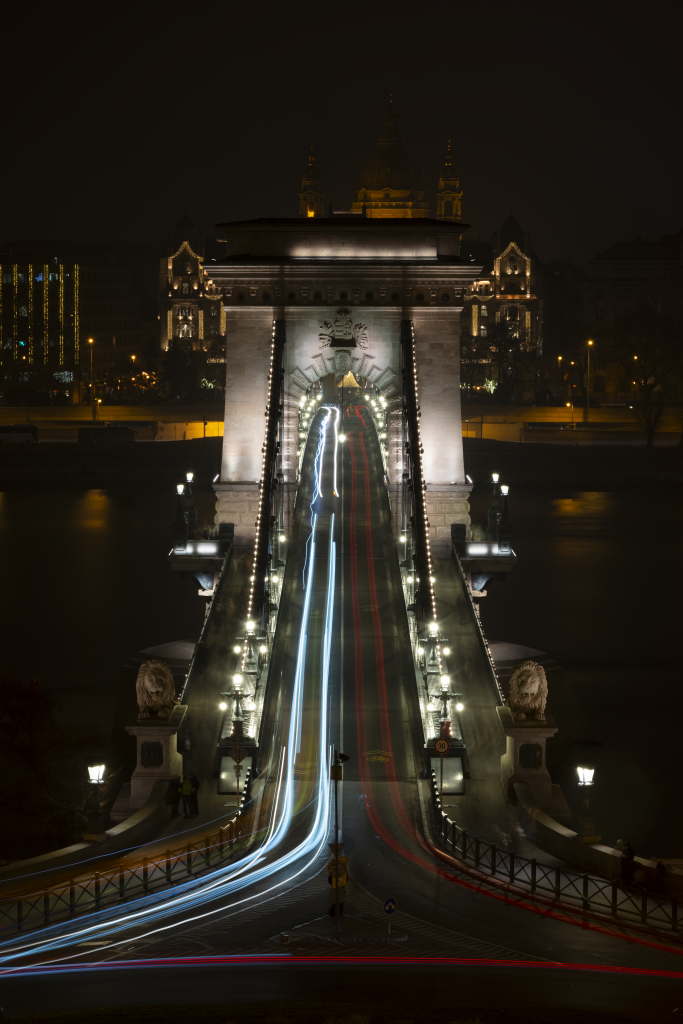 Symmetrical bridge view with flowing traffic light trails at night.
