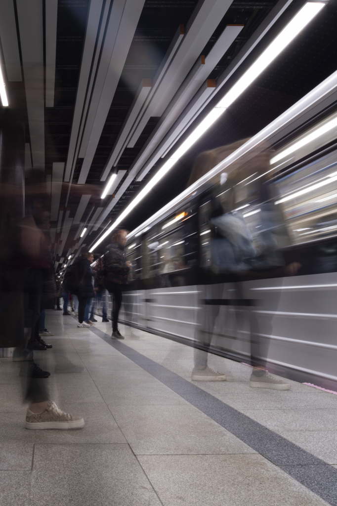 Blurred commuters on a platform with a moving train.