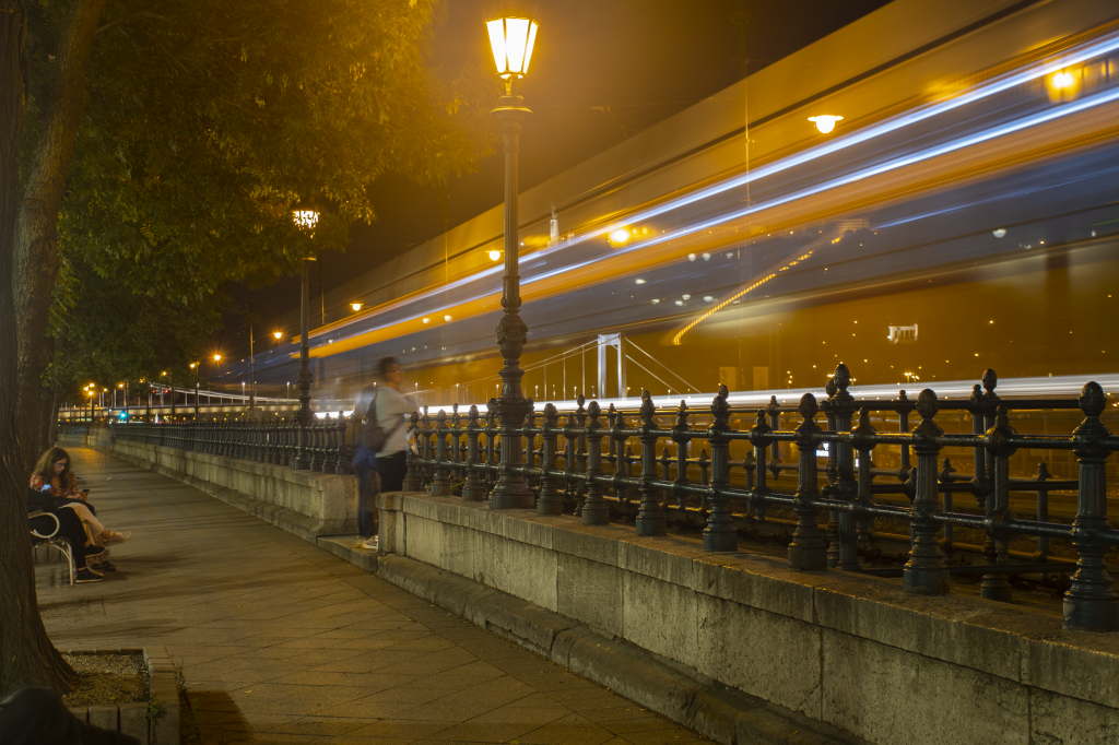 Riverside walkway with streetlights and blurred traffic.