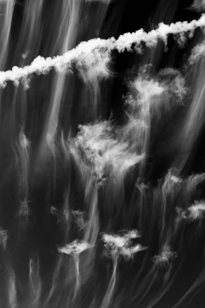 High cirrus clouds crossed by a thin contrail.