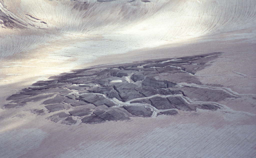 Cracked glacier surface with light and dark ice patterns.